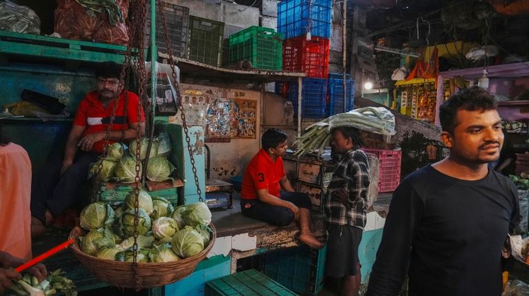 A vegetable vendor talks with a customer at a local...