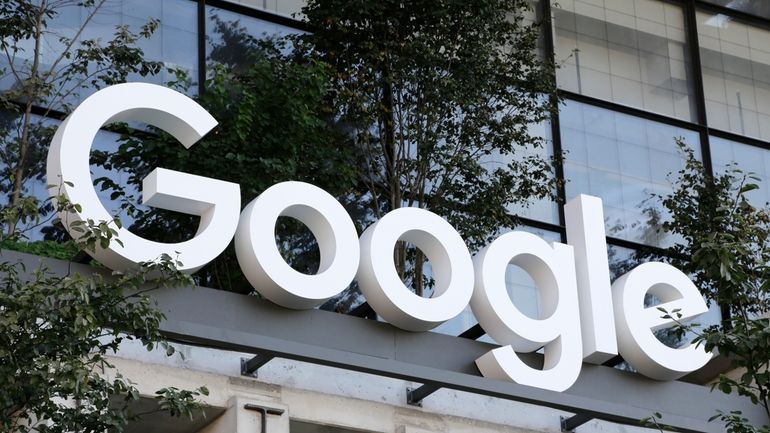 A Google sign hangs over an entrance to the company's...