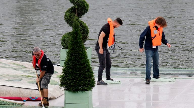 Maintenance workers sweep water off a skateboard ramp installed on...