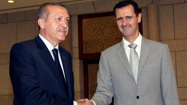 Syrian President Bashar Assad, right, shakes hands with Turkish Prime...