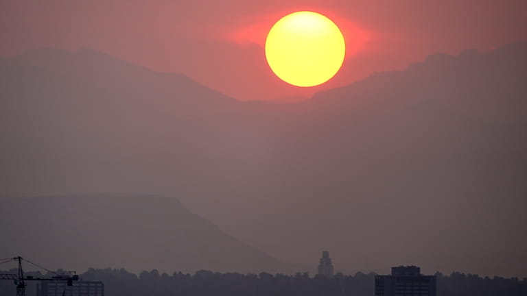 The sun sets behind the mountains obscured by wildfire smoke...