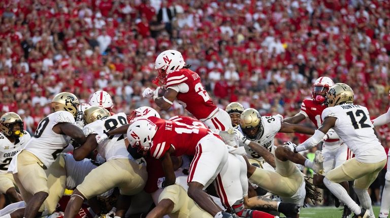 Nebraska's Dante Dowdell, top, leaps over Colorado defenders to score...