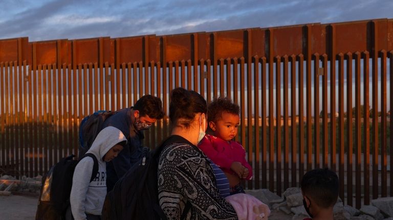 A pair of migrant families from Brazil wait to be...