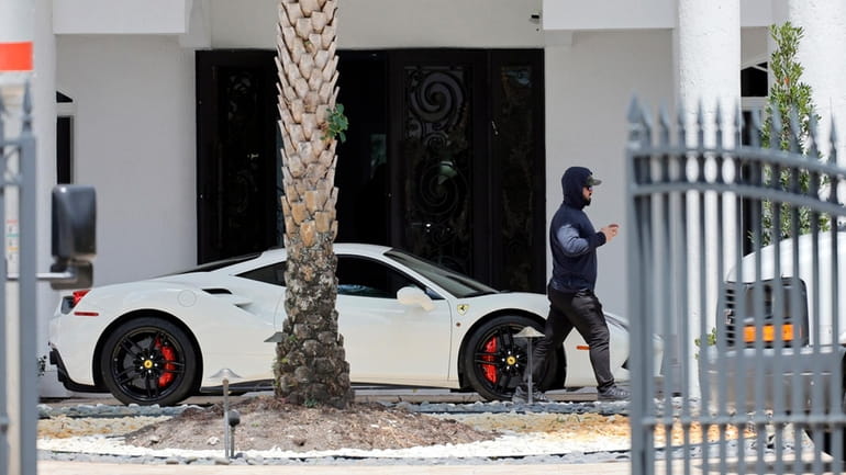 A man walks past a Ferrari in the driveway at...