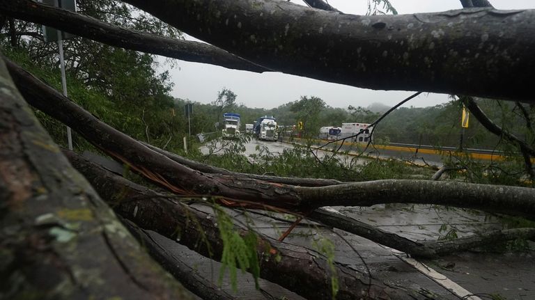 Trucks sit idle on a highway blocked by a landslide...