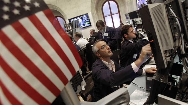 Traders work in a booth on the floor of the...