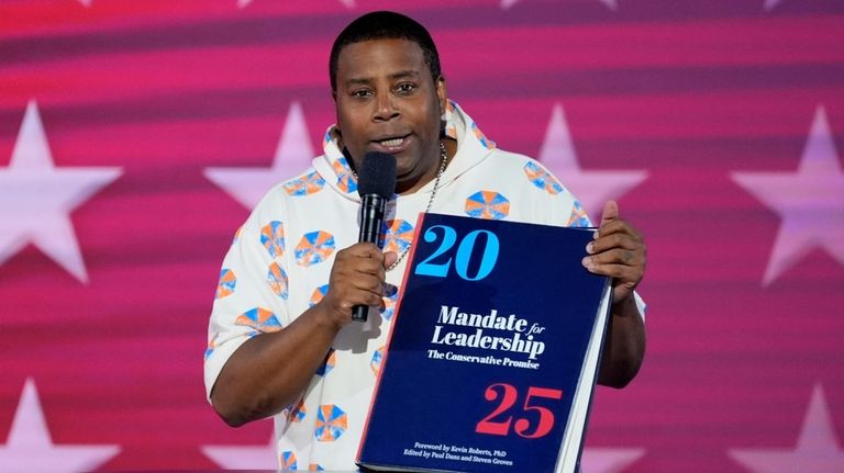 Kenan Thompson speaks as he carries a copy of Project...