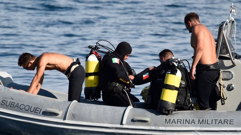 Italian Navy scuba divers work at the scene of the...