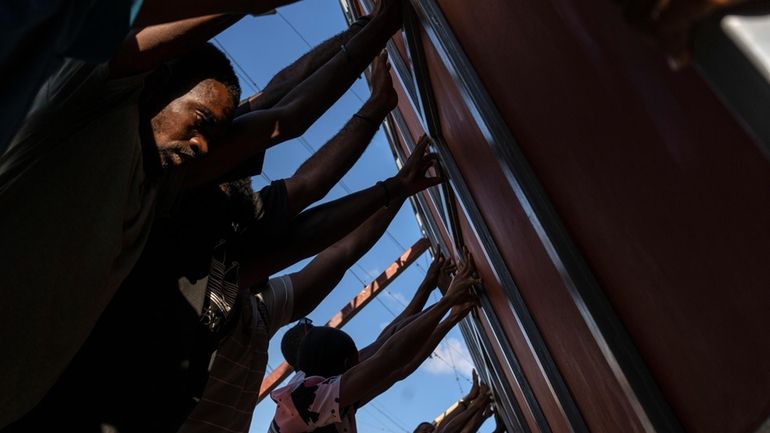 Neighbors raise a metal gate as they work to install...