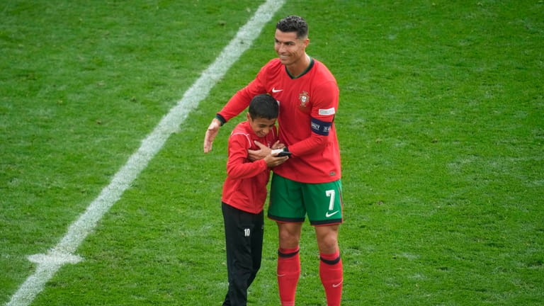 Portugal's Cristiano Ronaldo embraces a young pitch invader during a...