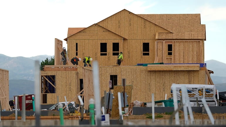 Workers toil on new homes in a housing development Tuesday,...