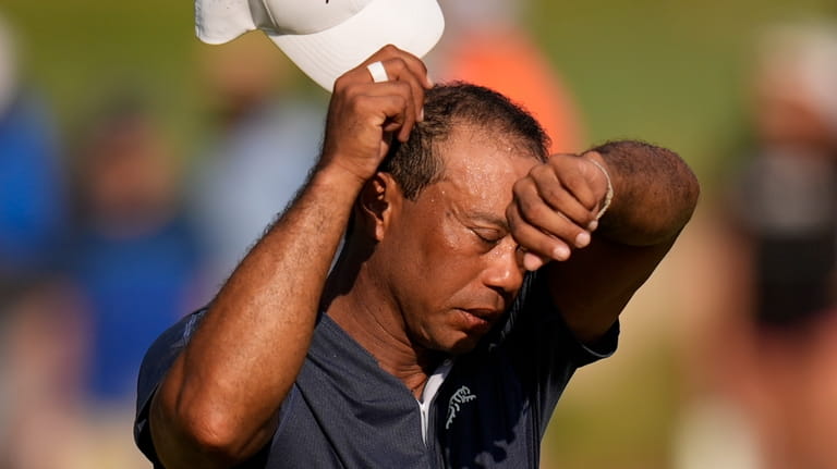 Tiger Woods wipes his face on the 16th hole during...