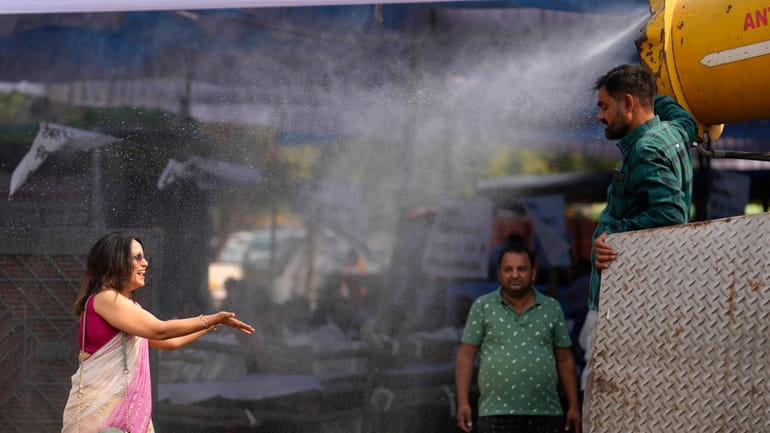 A polling official enjoys a cooling spray of water under...