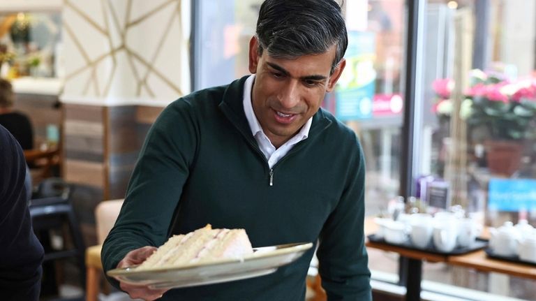 Britain's Prime Minister and Conservative Party leader, Rishi Sunak helps...