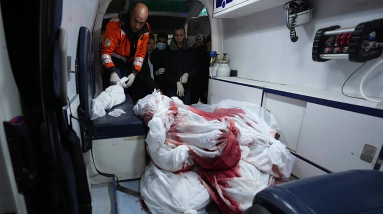 Medics unload bodies of Palestinians killed in the Israeli bombing...
