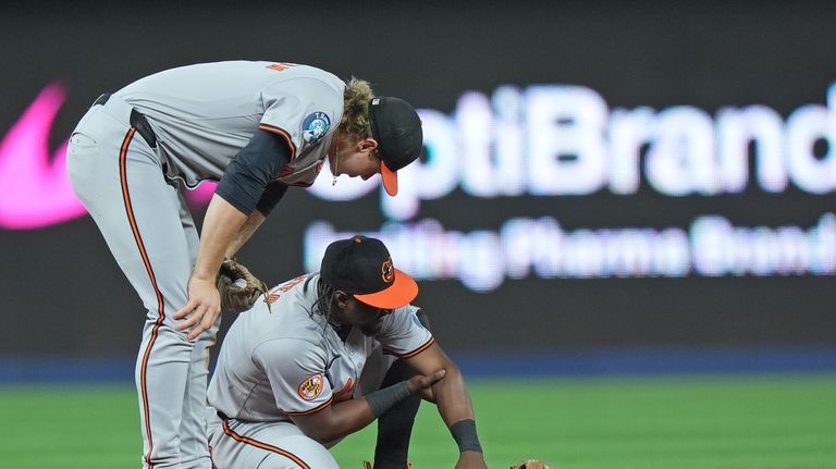 Baltimore Orioles shortstop Gunnar Henderson, left, checks on second baseman...