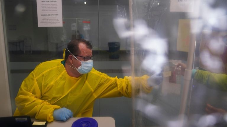 Sander Edmondson, an administrative worker, hands a COVID-19 testing kit...