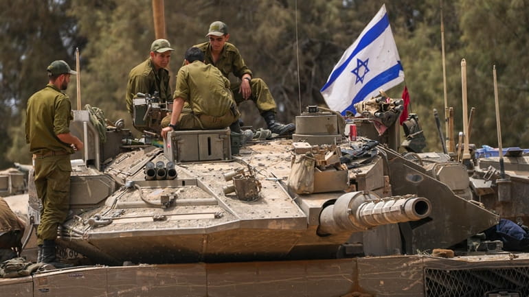 Israeli soldiers work on a tank near the Israeli-Gaza border,...