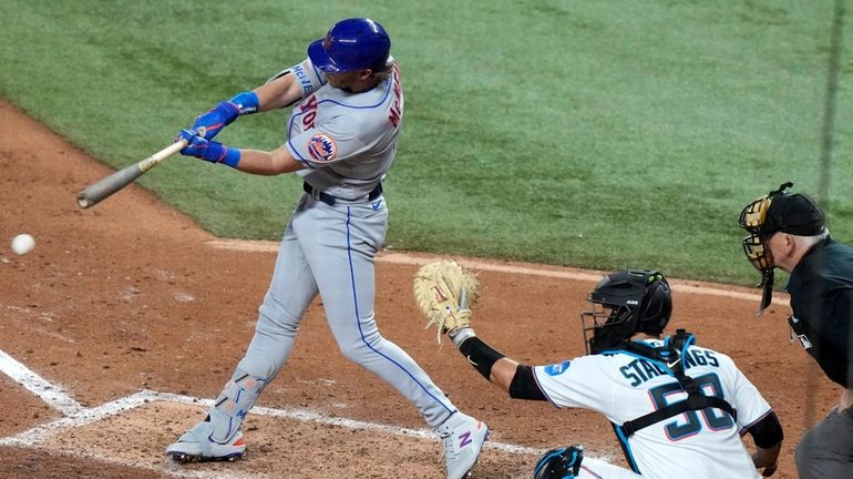 The Mets' Jeff McNeil, left, hits a single to score...