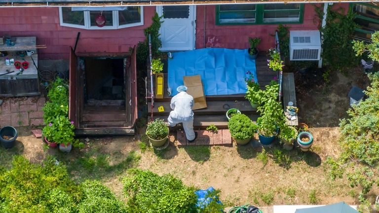 Investigators work in the backyard of Rex A. Heuermann's home in...