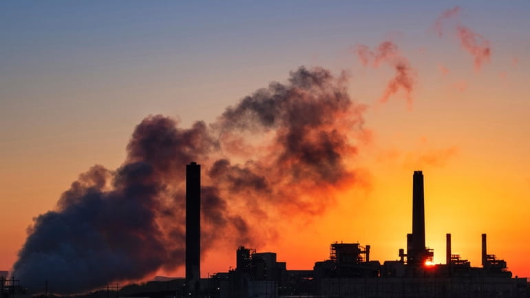 File - A coal-fired power plant is silhouetted against the...