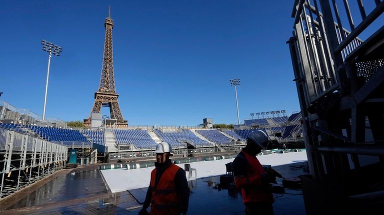 Workers remove grandstand seating as part of the dismantling of...