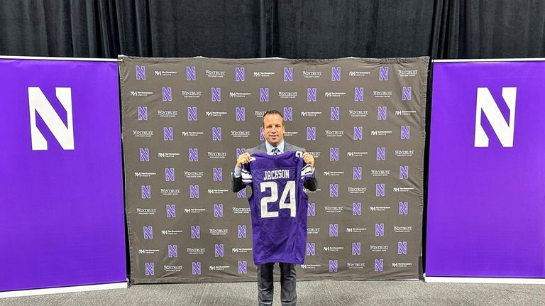 New Northwestern athletic director Mark Jackson holds up a jersey...