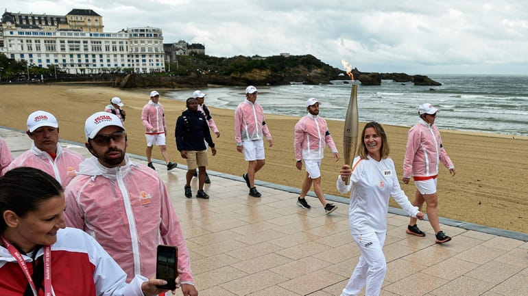 Zoe Grospiron carries the Olympic torch in Biarritz, southwestern France,...