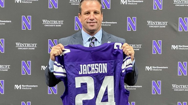 New Northwestern athletic director Mark Jackson holds up a jersey...