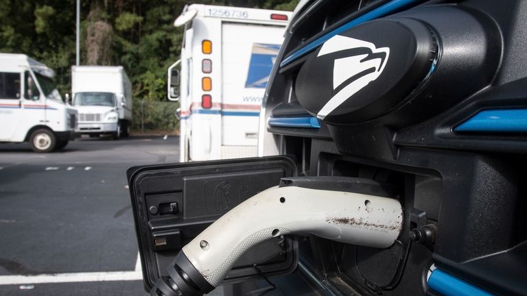 New mail delivery vehicles are charging at a station at...