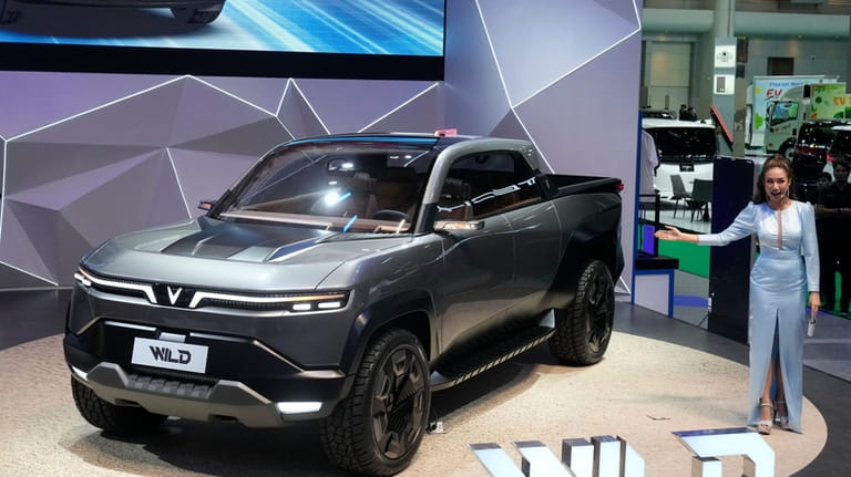 A Thai model poses next to Vinfast's electric concept pickup...