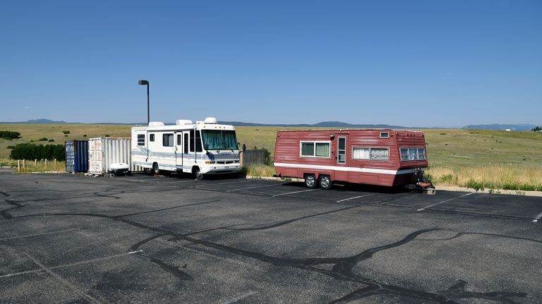 A recreational vehicle and camping trailer sit empty in The...