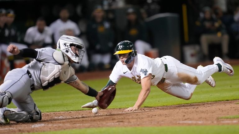 Oakland Athletics' Zack Gelof, right, slides home to score against...