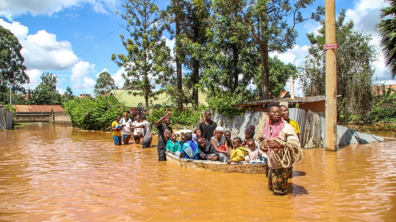 A family uses a boat after fleeing floodwaters that wreaked...