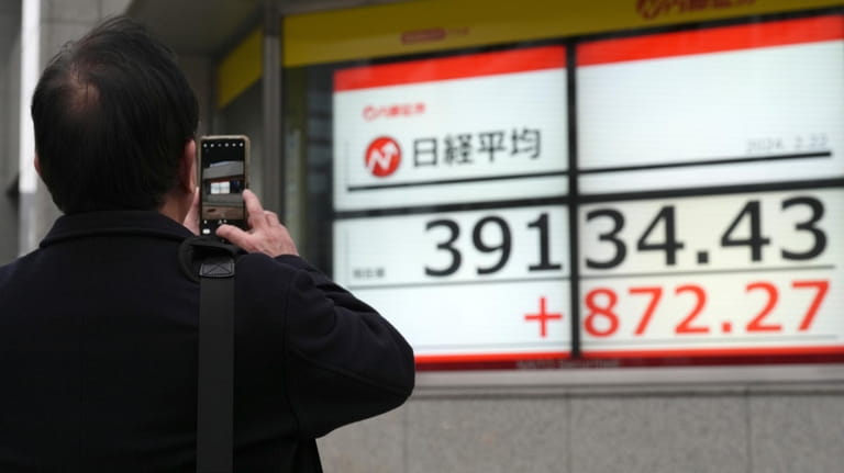 A person takes photograph an electronic stock board showing Japan's...