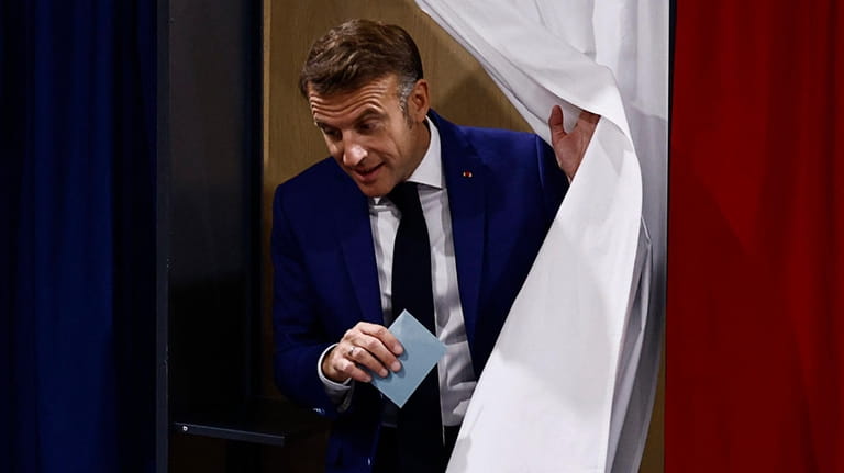 French President Emmanuel Macron leaves the voting booth before voting...