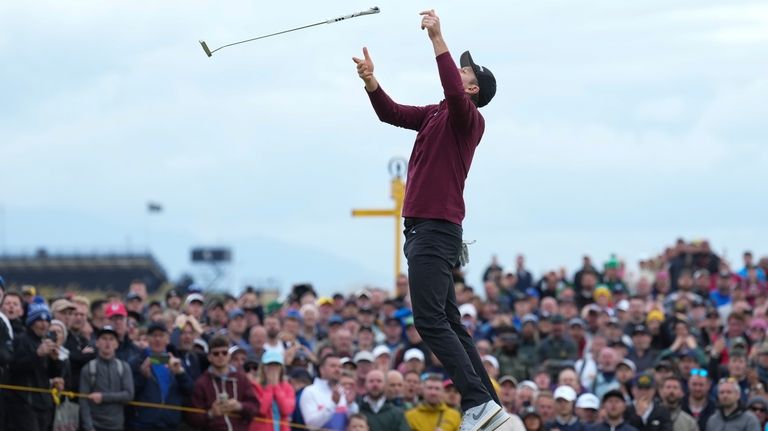 Justin Rose of England throws his putter in the air...