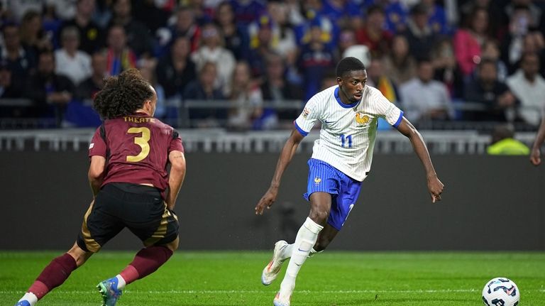 France's Ousmane Dembele, right, prepares to take a shot scoring...