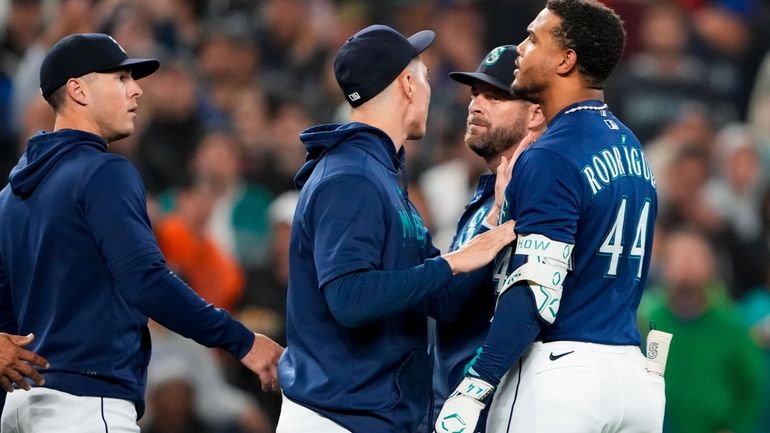 Seattle Mariners' Julio Rodriguez (44) is held back by teammate...