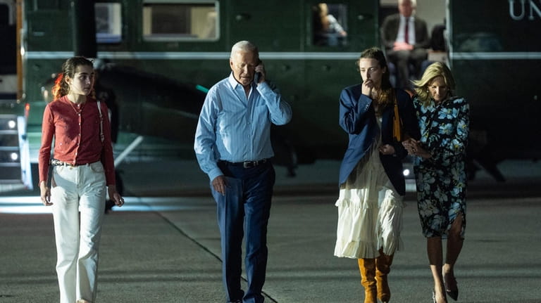 President Joe Biden talks on the phone as he walks...