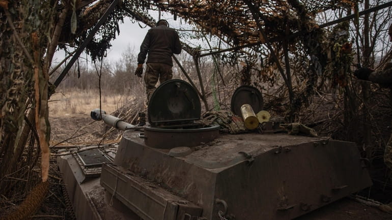 Ukrainian soldiers prepare a self-propelled artillery vehicle Gvozdika to fire...