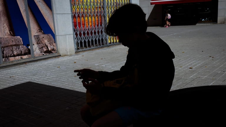 A 12-year-old boy plays with his personal phone outside school...