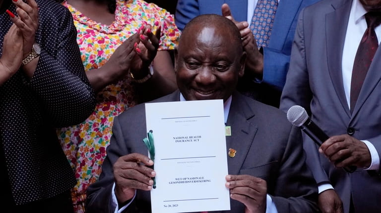 South African President Cyril Ramaphosa shows the signed bill for...