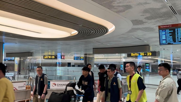A passenger, center, arrives from Bangkok at a Singapore airport...