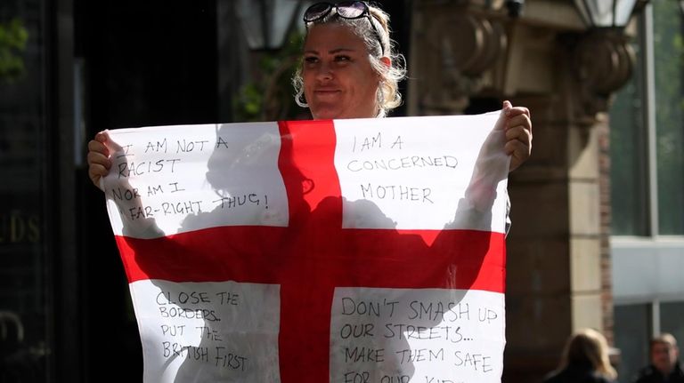 A woman holds the English flag ahead of a far-right...