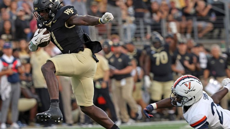 Wake Forest running back Demond Claiborne, left, gets past Virginia's...