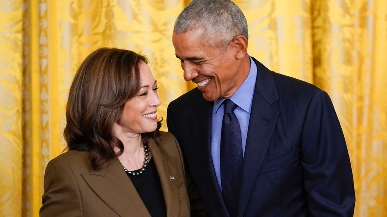 Former President Barack Obama talks with Vice President Kamala Harris...