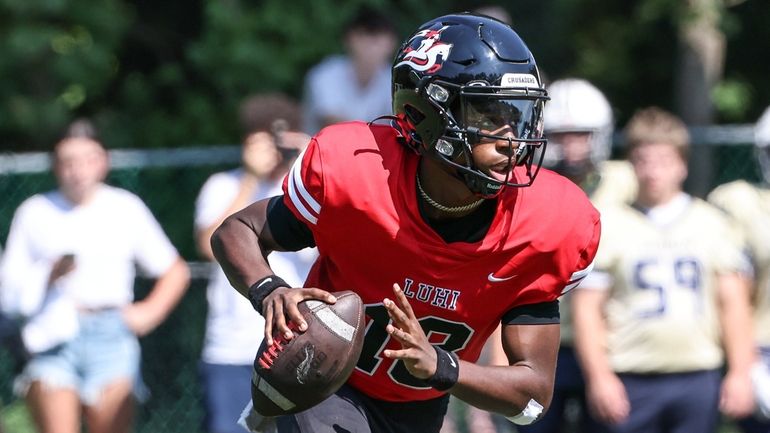 Long Island Lutheran's quarterback Peyton Robinson rolls out to pass...