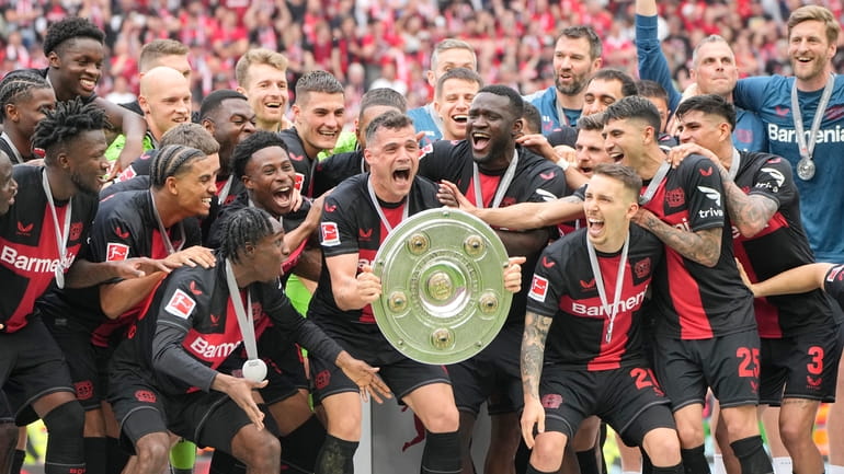 Leverkusen's Granit Xhaka, center, celebrates with the trophy as his...