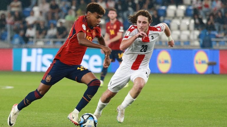 Spain's Lamine Yamal, left, challenges for the ball with Georgia's...